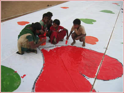 Street kids help paint the letter before the big event in Mumbai.